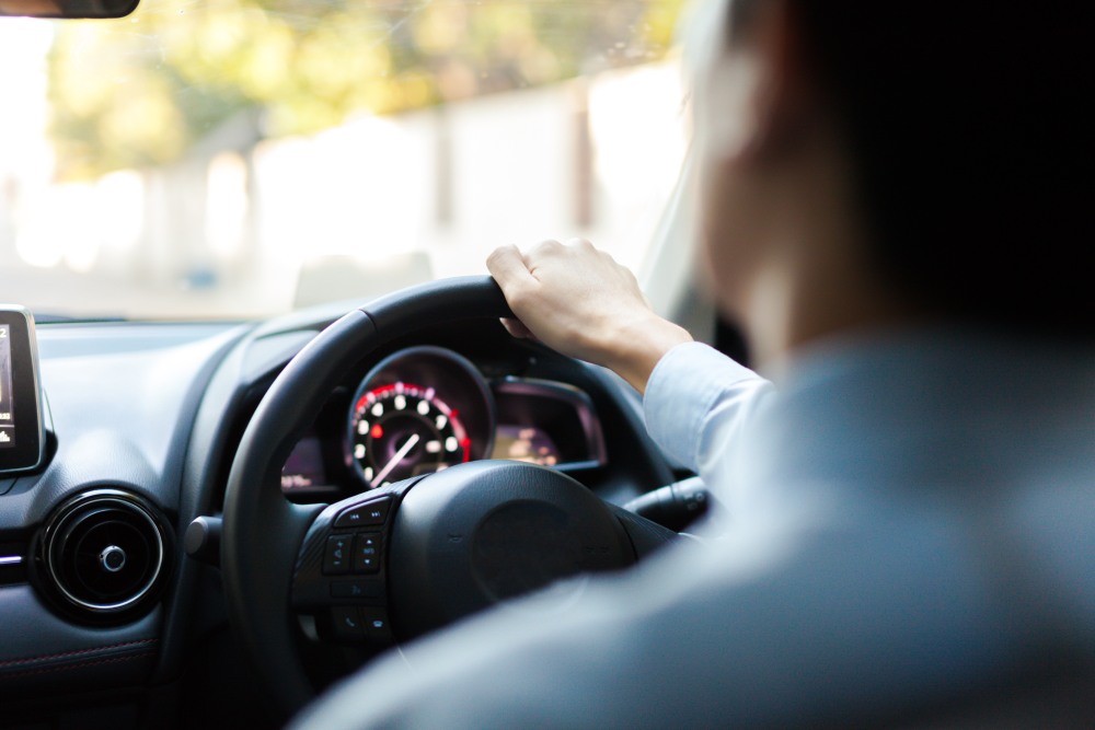 Close up of a young man with his hand on the steering wheel